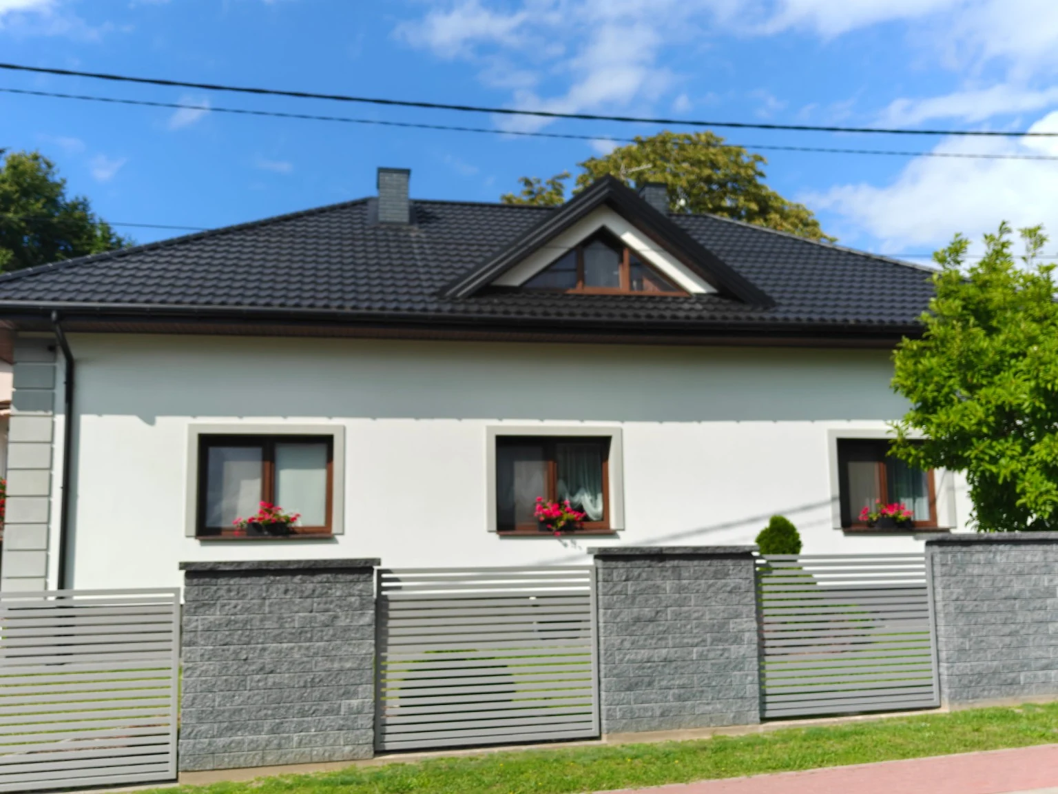 Istniejący parterowy dom z ogrodzeniem i kwiatami